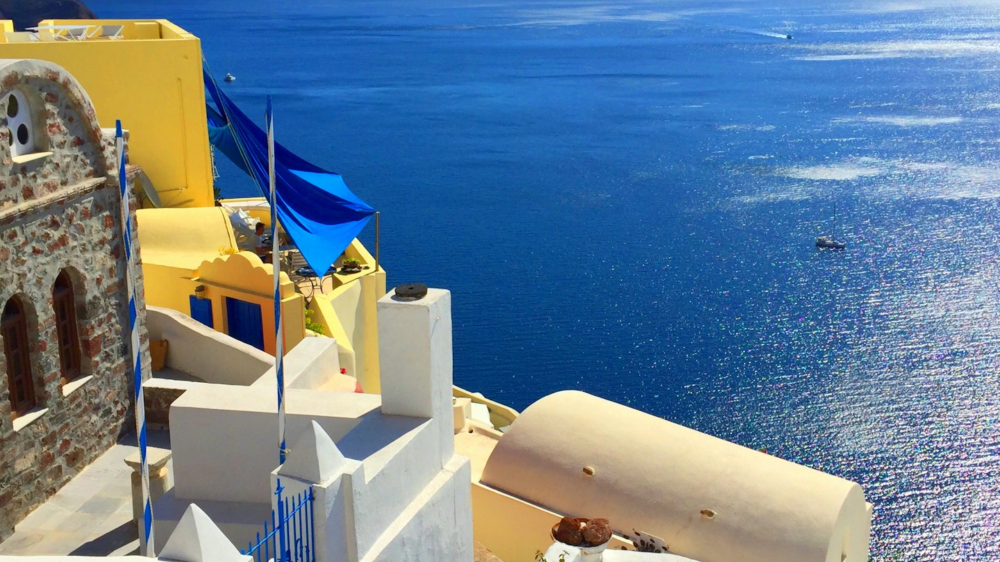 Whitewashed Mediterranean buildings with blue accents by the sea.