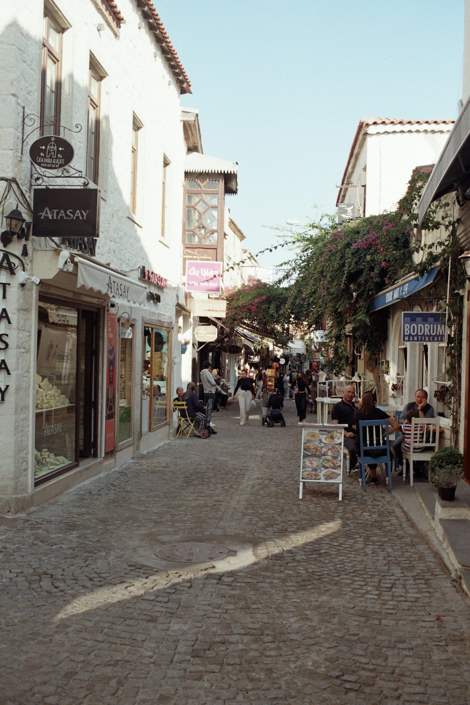 People dining and walking on a historic cobblestone street.